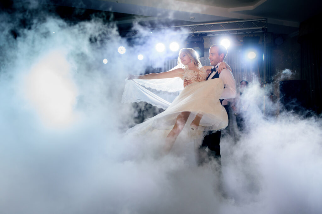 groom whirls bride in the smoke dancing for the first time